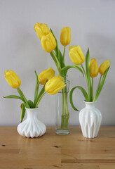 tulips in white ceramic and glass vase on a wooden table