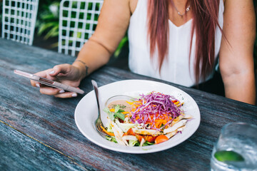 Crop young stylish woman using smartphone during lunch break