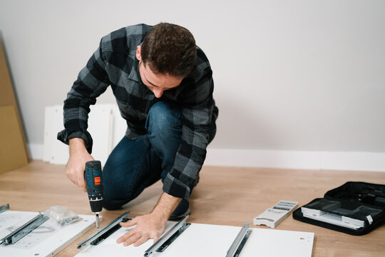 Portrait of man assembling furniture. Do it yourself furniture assembly.