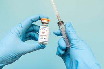 Coronavirus Vaccine in glass bottle in hand of doctor blue vaccine jar on white background. Vaccine Concept