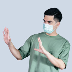 STOP! COVID-19 Coronavirus portrait handsome young asian .man wearing green shirt and mask protection from covid 19 isolated on gray background in studio. Asian man people. COVID-19 concept.