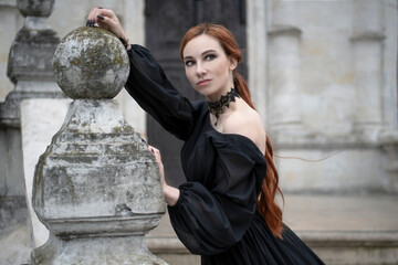 Red-haired woman in a gothic outfit at the door of an old temple