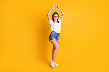 Fototapeta na wymiar Full length body size view of pretty cheerful slim brown-haired girl showing heart shape up isolated over bright yellow color background