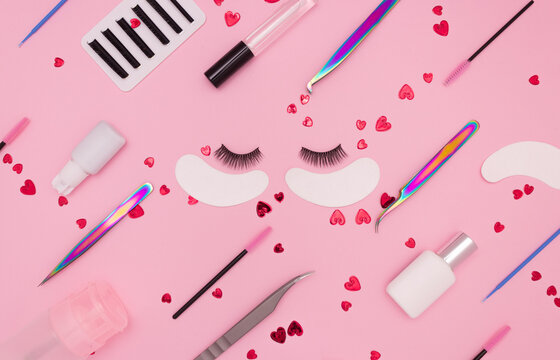 Eyelash extension tools, artificial eyelashes and red hearts on a pink background. Tools for the lashmaker. The view from the top.