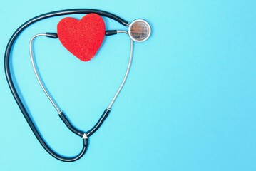 Close-up of a heart and a stethoscope on a blue background, top view. Global health care concept. caring for heart health. treatment with tablets and ampoules