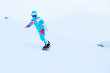 woman snowboarder is snowboarding from the slope