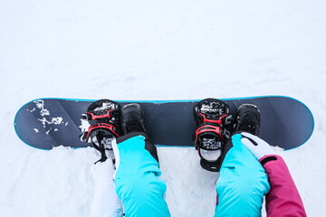 woman snowboarder puts on a snowboard close up