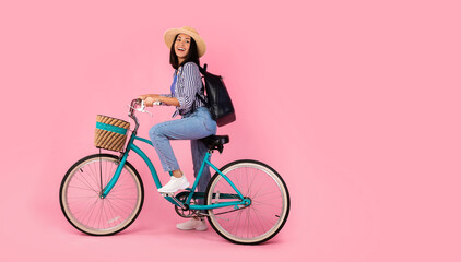 Excited asian woman riding retro bicycle with wicker basket