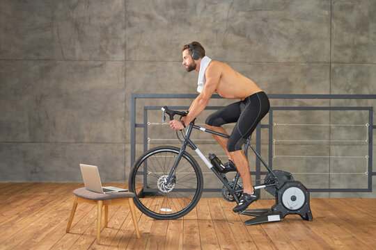 Athletic Young Man Having Stationary Bike Workout At Home