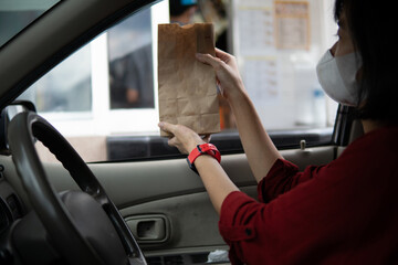 asian woman drivethru taking order while sitting inside the car. food order