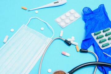 Scattered white pills on blue table.Medical, pharmacy and healthcare concept. Blue background white pills with a medical statoscope, top view.