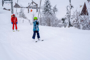 AURON, FRANCE-01.01.2021: Professional ski instructor and child lifting on the ski drag lift rope...