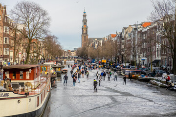 People ice scating on frozen canal in city center of Amsterdam