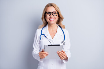 Portrait of charming positive lady arms hold tablet wear spectacles toothy smile isolated on grey color background