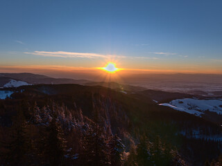 Stunning sunset viewed from Eugen-Keidel-Turm on the top of Schauinsland peak, Germany with beautiful view over the foothills of Black Forest, Rhine valley and Vosges mountains on horizon in winter.