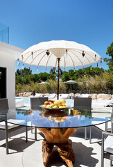 mesa no exterior com fruta, perto da piscina com chapéu de sol exótico 