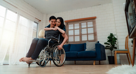An asian man in a wheelchair in the home after a car accident and his wife to give encouragement. The concept of Mutual care and new technology has made people with disabilities Equality in society.