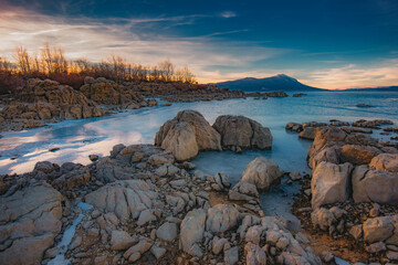 winter landscape with rocks on the shores of the lake