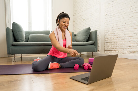 Attractive woman on laptop in virtual online fitness class working out at home