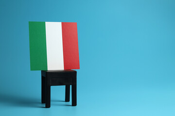 National flag of Italy on a black chair, light blue background. Communication and dialog concept.