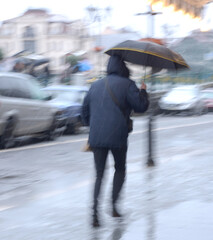 Woman with umbrella walking down the street in winter day in motion blur