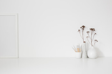 Creative desk with a blank space, desk objects, drawing supplies, pencils, brushes, and plant near bright wall. Artist workspace.	
