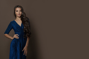 Perfect gorgeous brunette model woman in blue evening gown posing on brown background