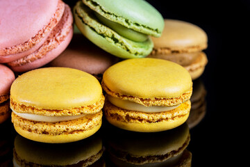 Close-up of French dessert for coffee. Multicolored macarons on black background