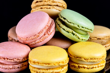 close up multicolored macarons on black background