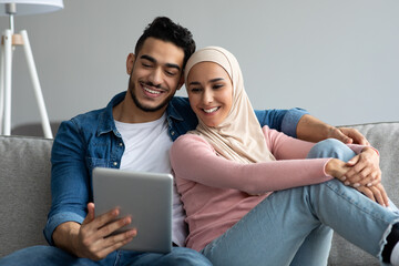 Happy middle-eastern couple looking at digital tablet screen