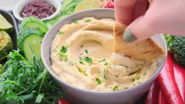 Traditional hummus in gray bowl with vegan snacks. Plant based diet concept.