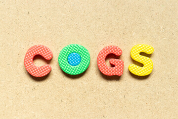 Foam alphabet letter in word COGS (Abbreviation of Cost of goods sold) on wood background