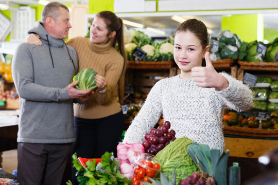Portrait of satisfied tweenage girl during family shopping in fruit store