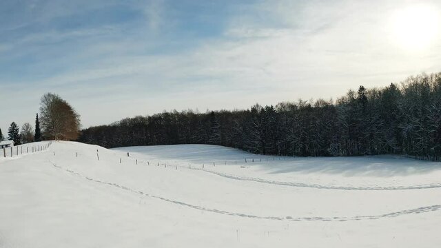 Wonderful winter weather - timelapse of moving white clouds over a snowy hill, where a father and his son have some skking fun in the background