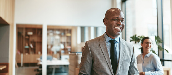 African American businessman laughing while walking through a modern office