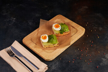 Healthy rye toast with avocado, egg, feta cheese on plate