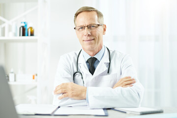 Handsome male doctor in glasses sitting at the table at work