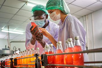 African and Caucasian specialists of beverage check quality of red juice in automatically product line of beverage industry