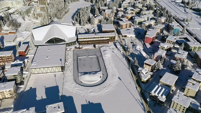 Davos, Switzerland: Aerial view of famous Swiss Alpine ski resort town in winter, buildings and slopes covered in snow - landscape panorama of Alps mountain range from above, Europe