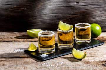 Mexican Gold Tequila with lime and salt on rustic wooden background. Alcoholic drink concept. Mexican national drink copyspace
