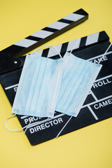 Naklejka premium clapperboard and medical masks on yellow, cinema concept