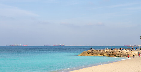 A few tourists and residents of the city walk along the embankment against the backdrop of the Mediterranean Sea in Haifa city, in northern Israel.
