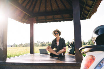 Pretty Caucasian copywriter smiling in perfect place for doing distance job via modern netbook...