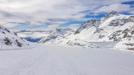 Fototapeta na wymiar Beautiful and serene landscape of mountains covered with snow in Moelltaler Gletscher, Austria. Thick snow covers the slopes. Clear weather. Perfectly groomed slopes. Massive ski resort.