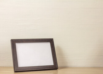 An empty wooden photo frame on a table or shelf with a copy of the space.