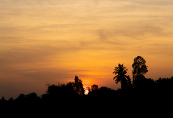 Sunset in the mountains, red and yellow sky behind and trees in the forefront