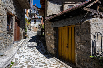 Fototapeta na wymiar Stone houses of traditional architecture and cobble-stone narrow street in the town of Metsovo, Greece