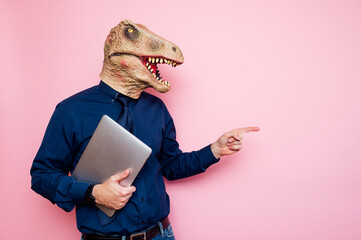 Euphoric man with dinosaur head using laptop