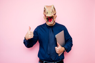 Euphoric man with dinosaur head using laptop