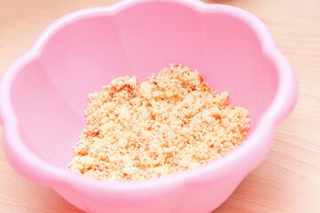 Dough made from crushed biscuit and mascarpone for baby cakes in a pink plastic bowl 